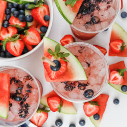 party cups filled cocktails and garnished with watermelon and berries