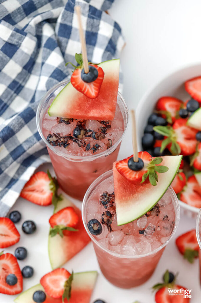 party cups filled with a watermelon berry drink with a fresh fruit garnish