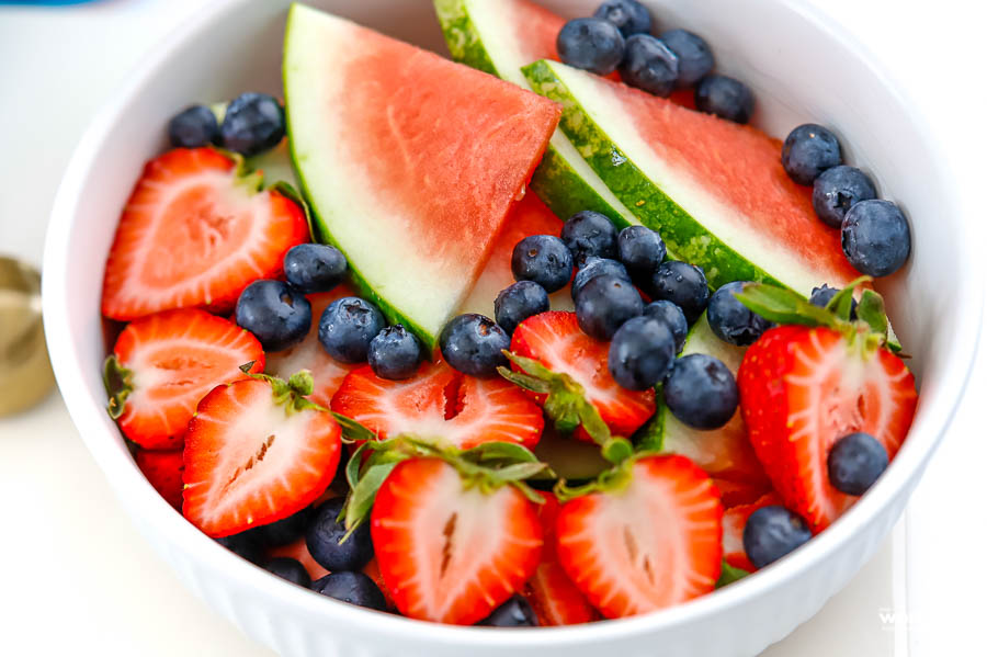 a white serving bowl filled with fresh fruit