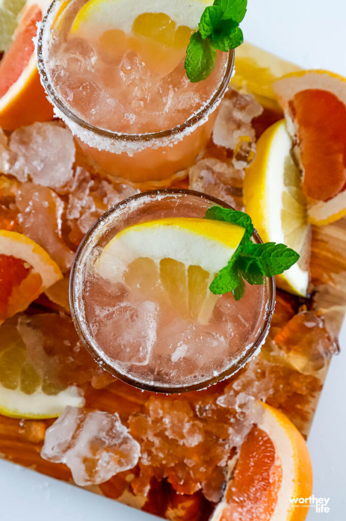 two serving of a paloma cocktail surrounded by palomas and grapefruit