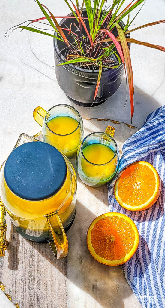 glasses of 100% orange juice in a cup and pitcher