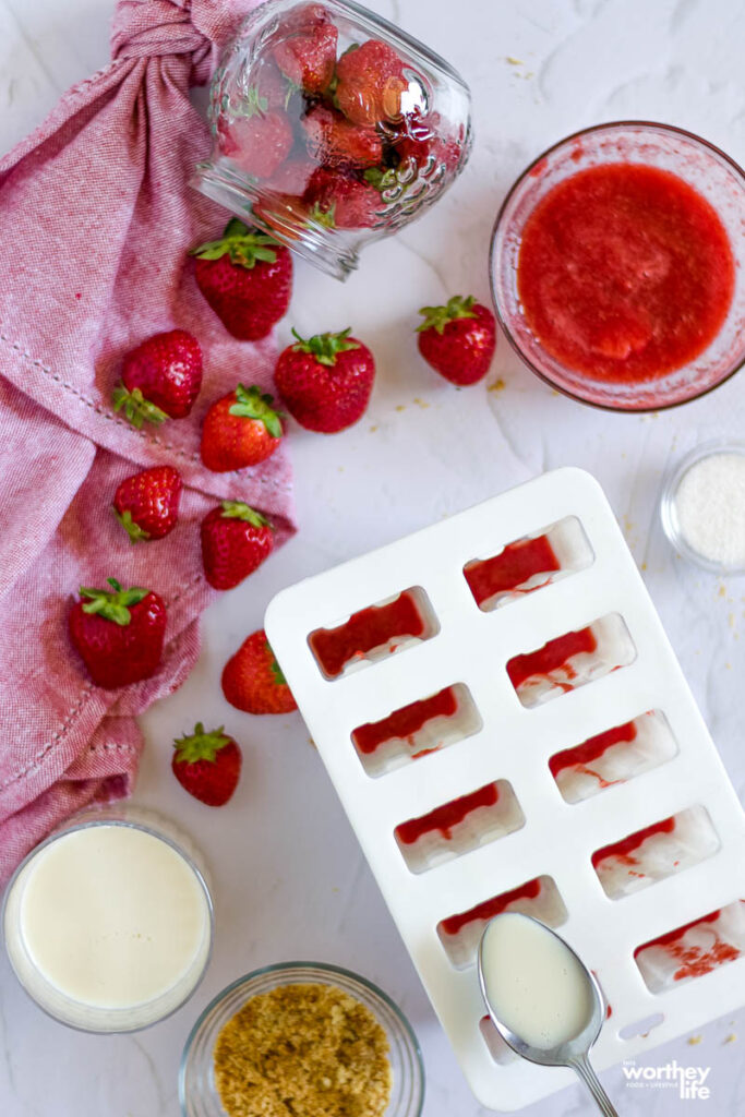 the making of frozen popsicles with strawberries