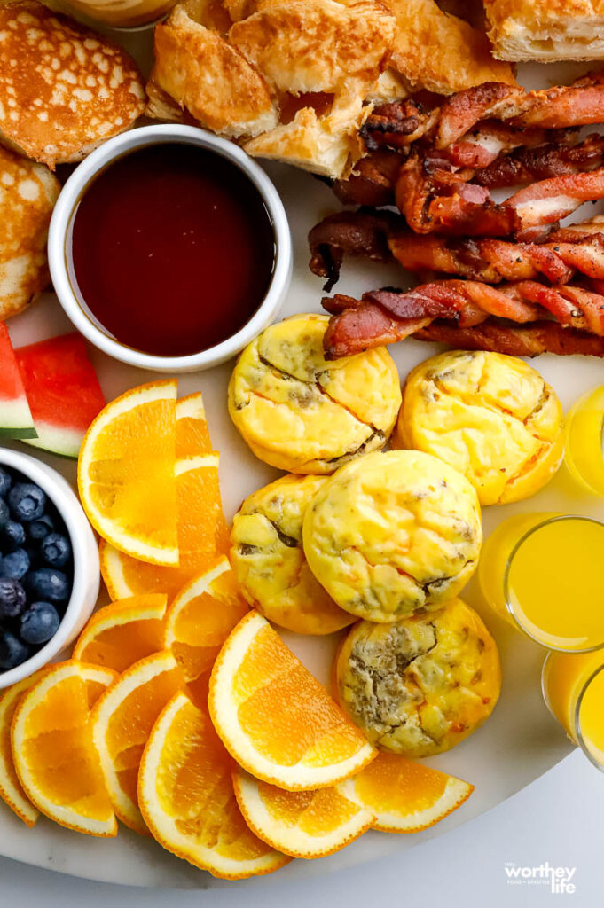 a platter filled with foods like pancakes, bacon, and egg bites