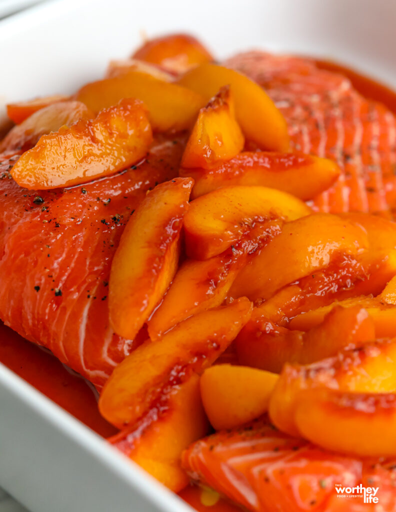 Salmon filet covered with fresh peaches in baking pan