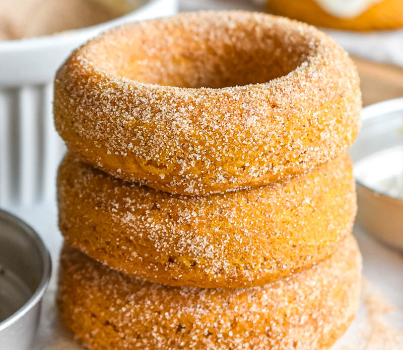 stacked homemade pumpkin doughnuts on white background