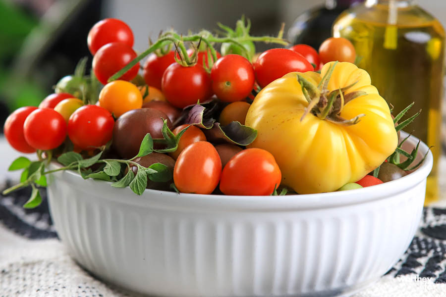 a scalloped white serving bowl filled with colorful tomatoes