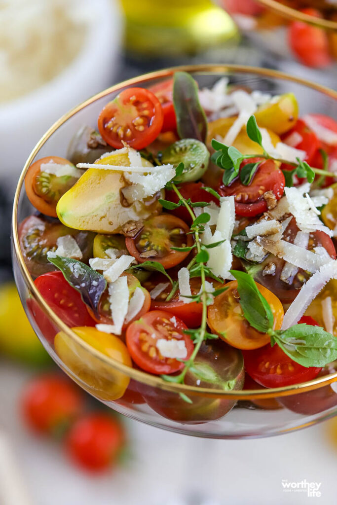 gold rimmed coupe glass filled with a colorful Cherry Tomato Salad with grated cheese