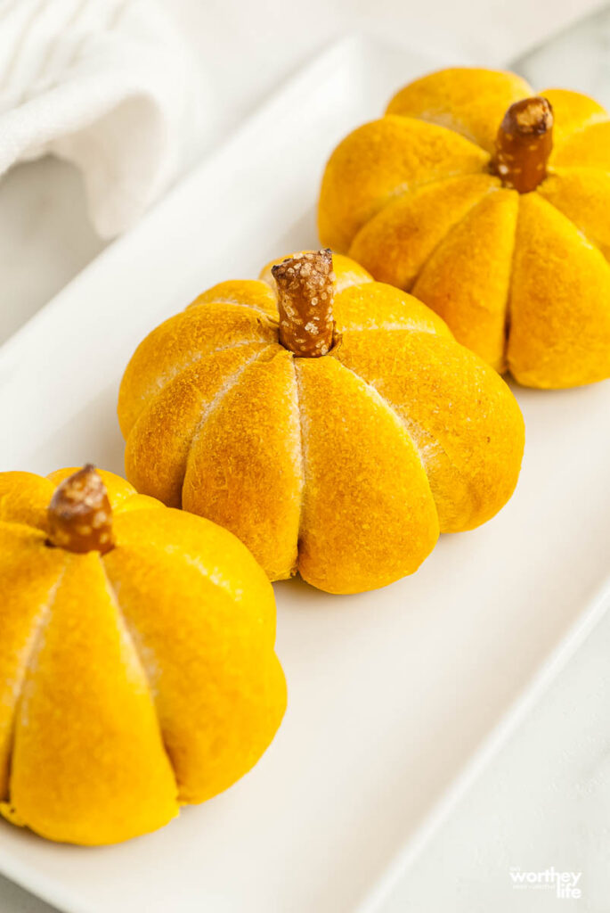 pumpkin dinner rolls in a row on white background