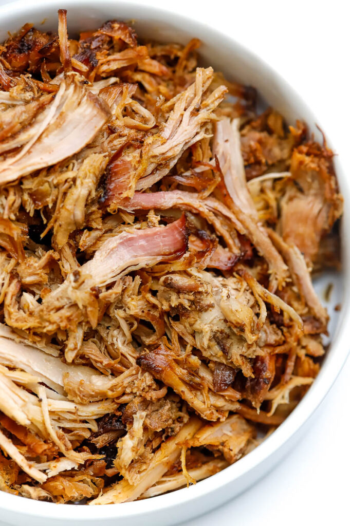a white serving bowl filled with tender smoky pulled pork