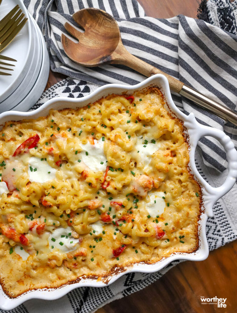 homemade mac + cheese in white casserole dish with wooden spoon