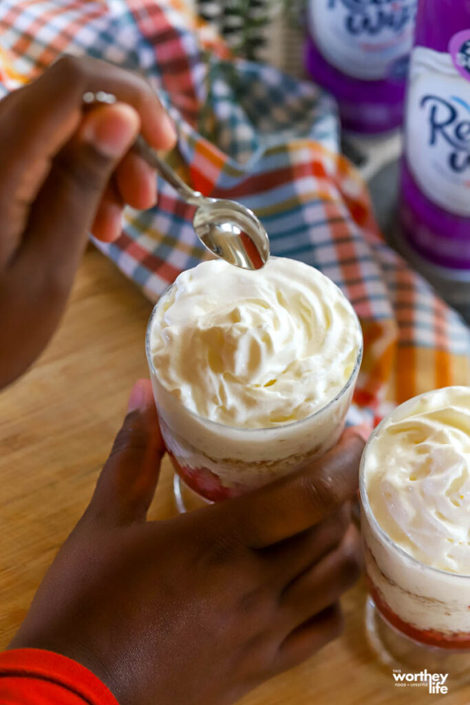 hand with spoon dipping into cranberry trifle