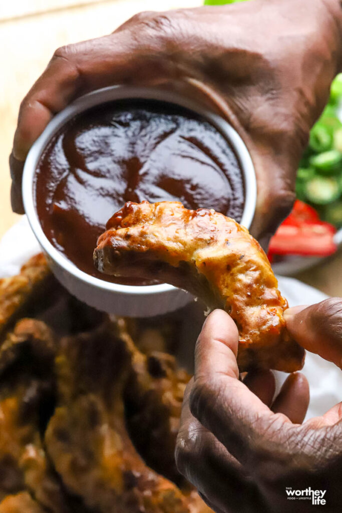 hand dipping ribs into bbq sauce