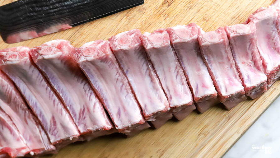 slab of cut baby back ribs on wood cutting board