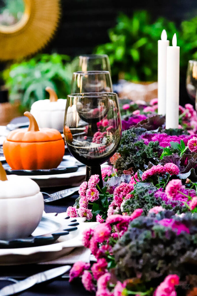 black wine glasses on table with purple mums and kale