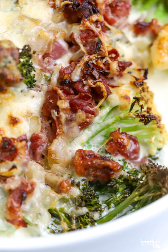 a white baking dish with broccoli, cheese and prosciutto 