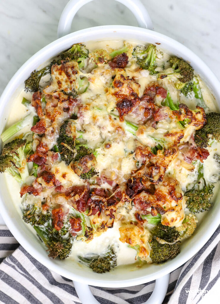 Broccoli with Prosciutto & Cream Gruyère sauce in white dish