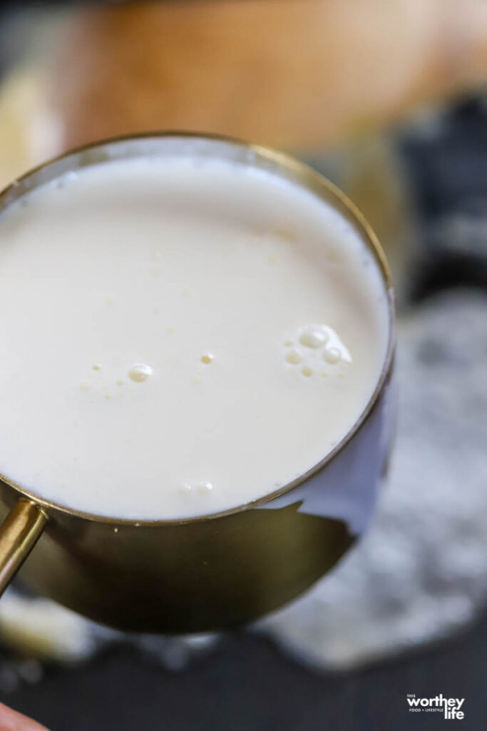 heavy whipping cream in gold measuring cup