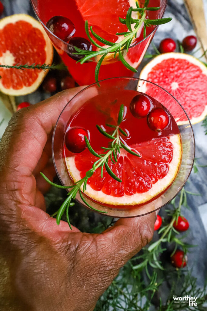 man holding a cranberry cocktail in hand