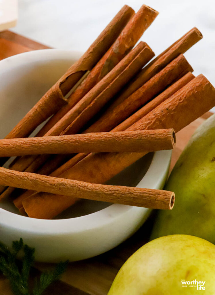 cinnamon sticks in a bowl surrounded by pears