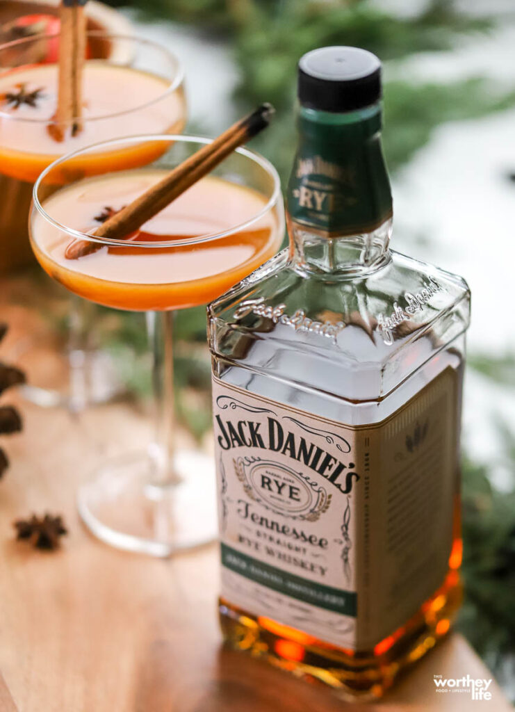 persimmon cocktail in a coupe glass and a bottle of rye whiskey