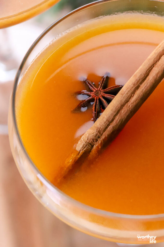 persimmon cocktail in a coupe glass garnished with star anise and a cinnamon stick