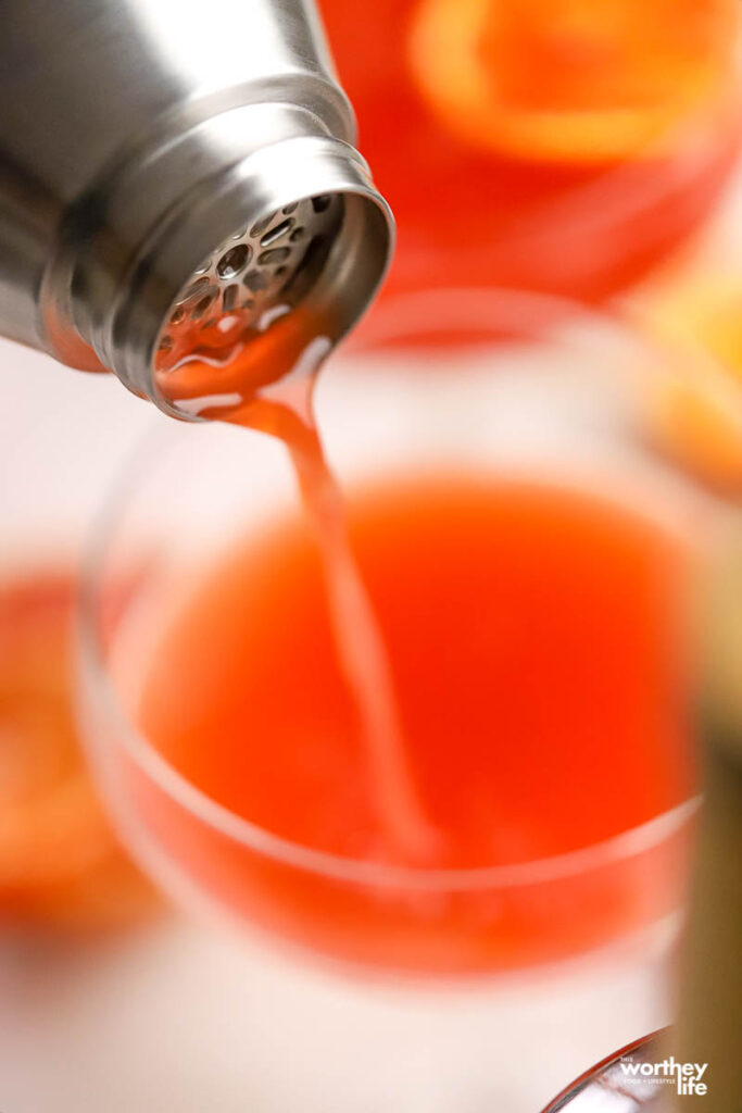 pouring a cocktail from cocktail shaker into glass