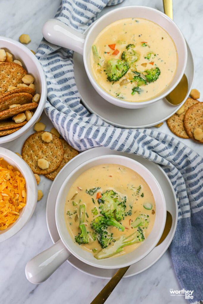 two bowls of broccoli cheddar soup with crackers