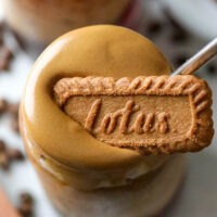 a glass topped with dalgona coffee and a cookie