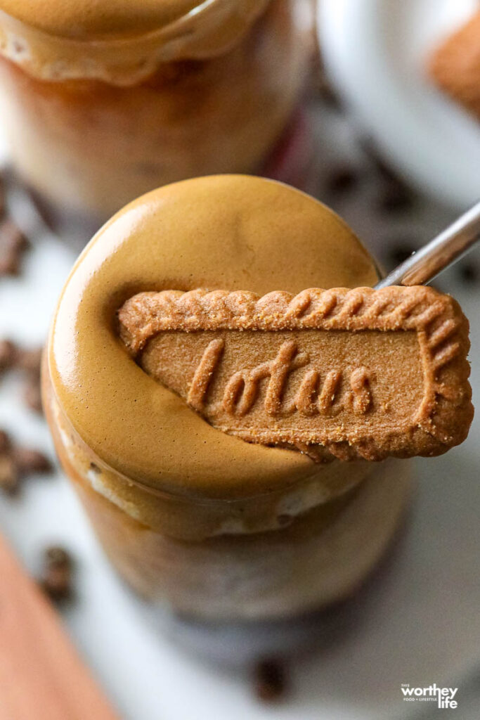 a glass topped with dalgona coffee and a cookie