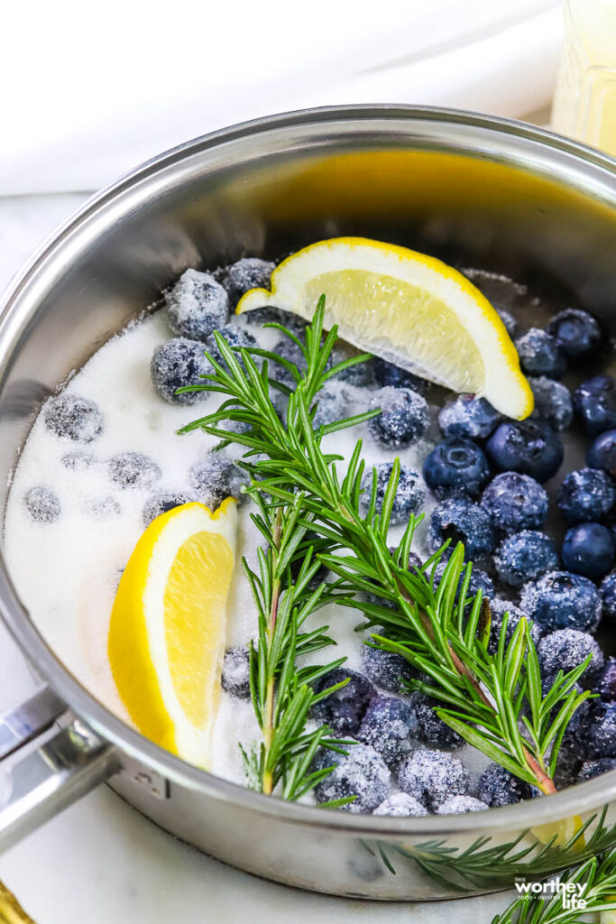 a sauce pot filled with blueberries, lemon wedges, sugar, and rosemary