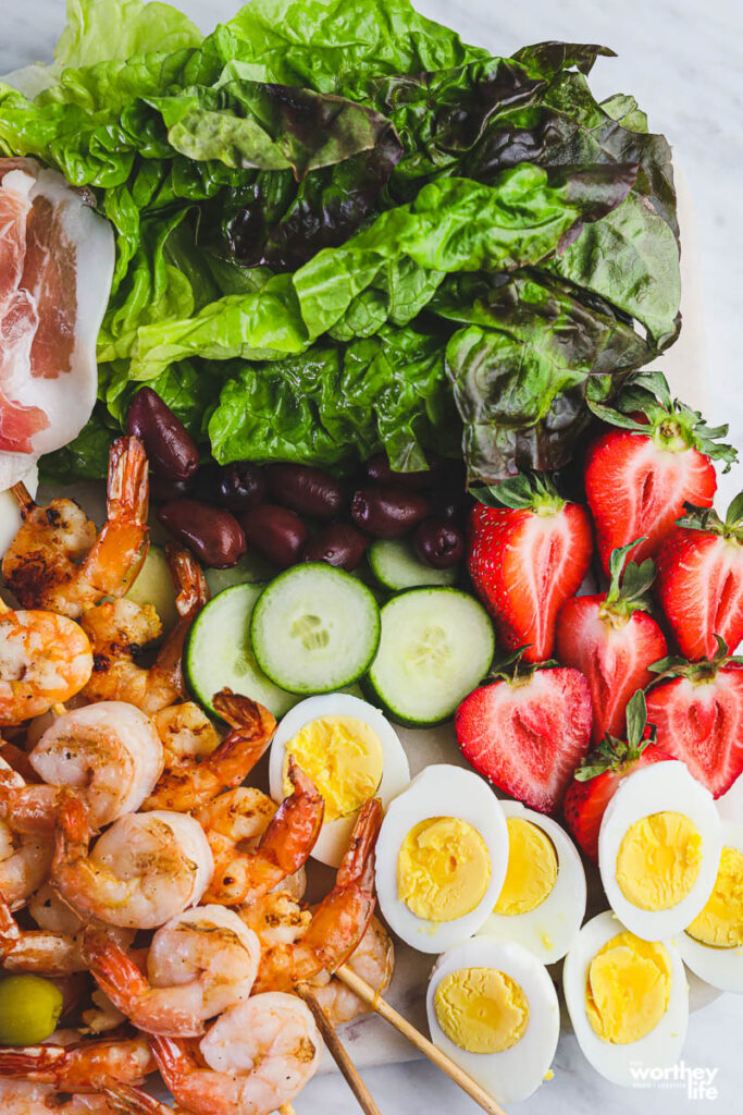 fresh veggies, shrimp and deviled eggs on white cutting board