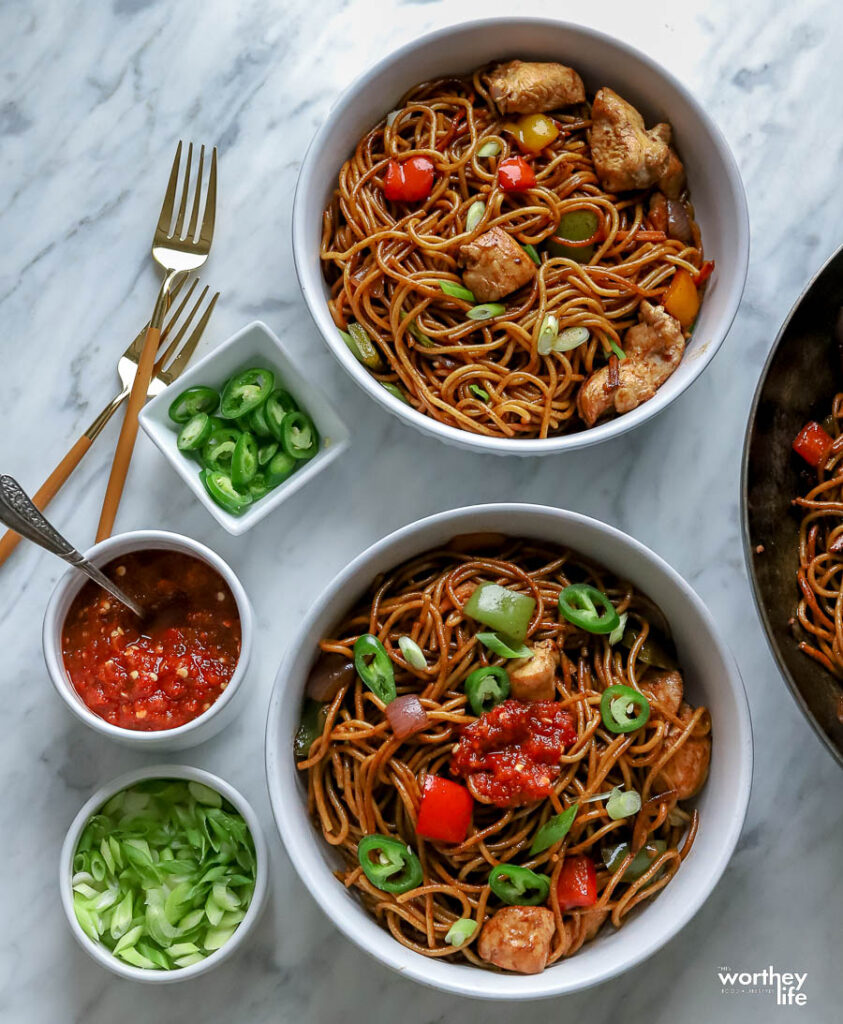 Chicken Lo Mein served in two white bowls with toppings and forks