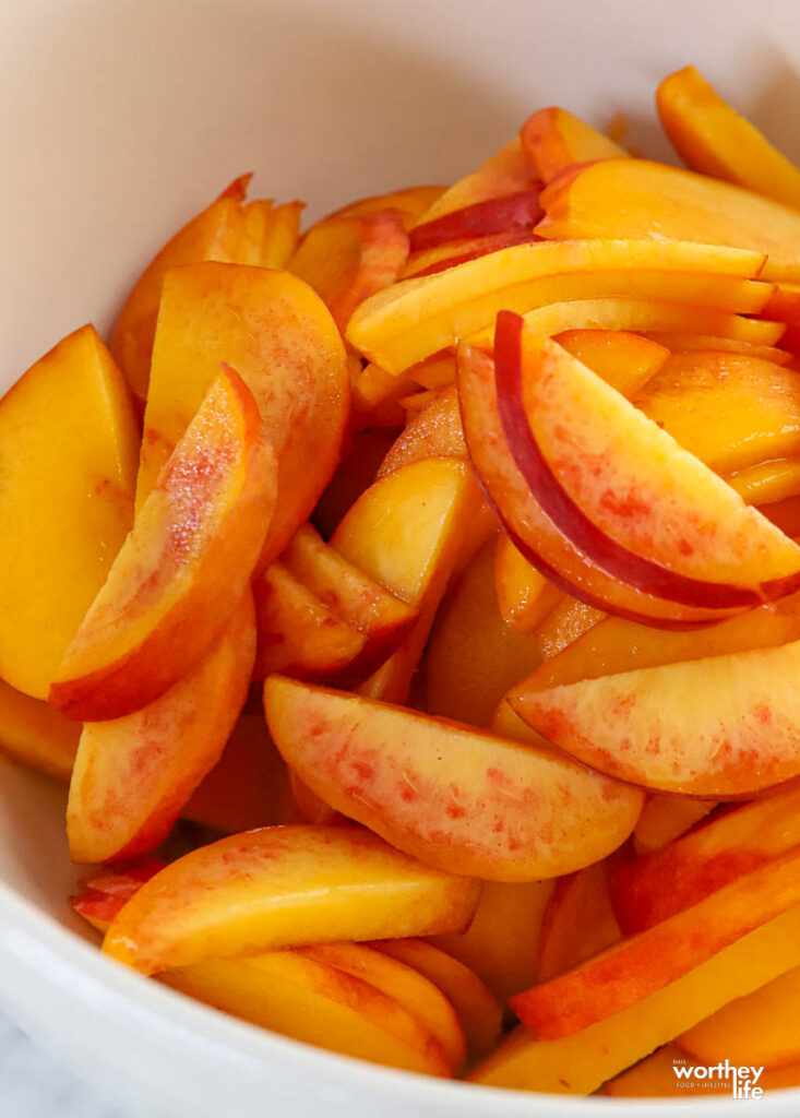 sliced peaches inside of a white mixing bowl