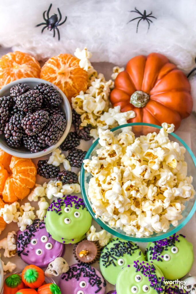 popped popcorn in bowl with treats on a Halloween board