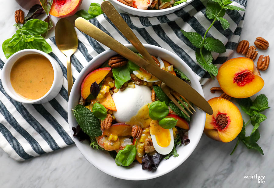 a white bowl with a peach burrata salad with silverware