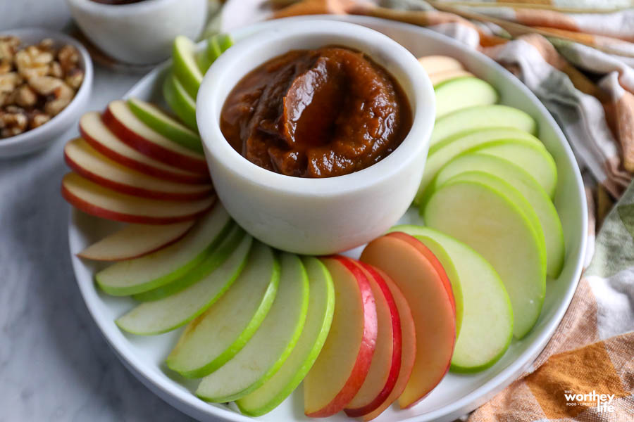 a white platter with red and green apple slices with pumpkin butter