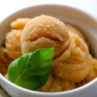 a white ramekin filled with apple pie sorbet and fresh basil