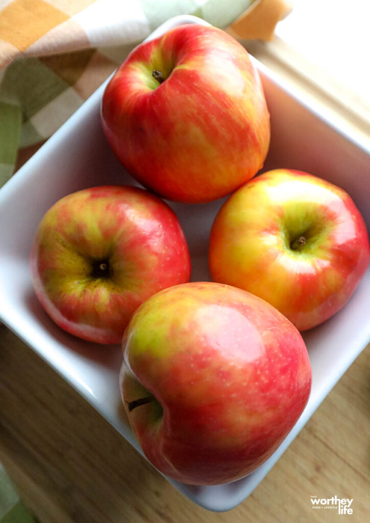 a white square bowl filled with four apples