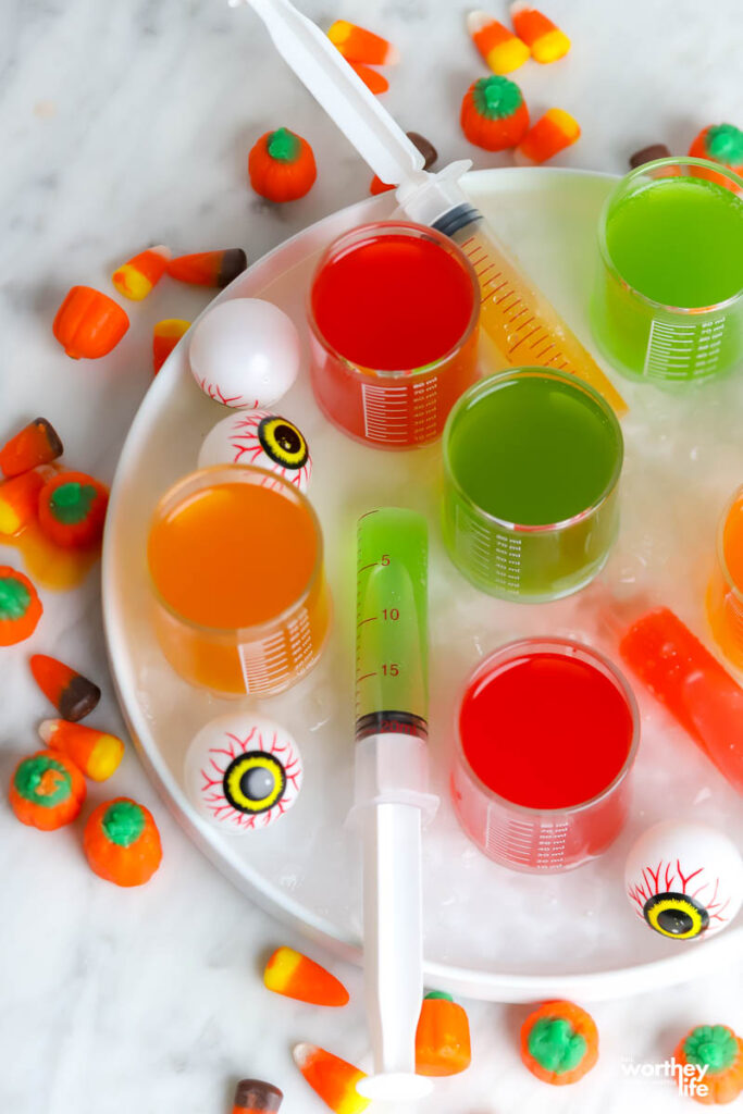 five shot glasses filled with colorful drinks for Halloween