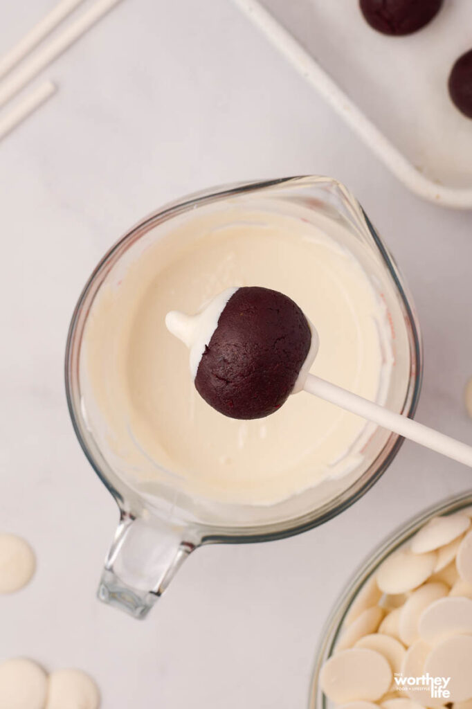 dipping a cake ball into white frosting