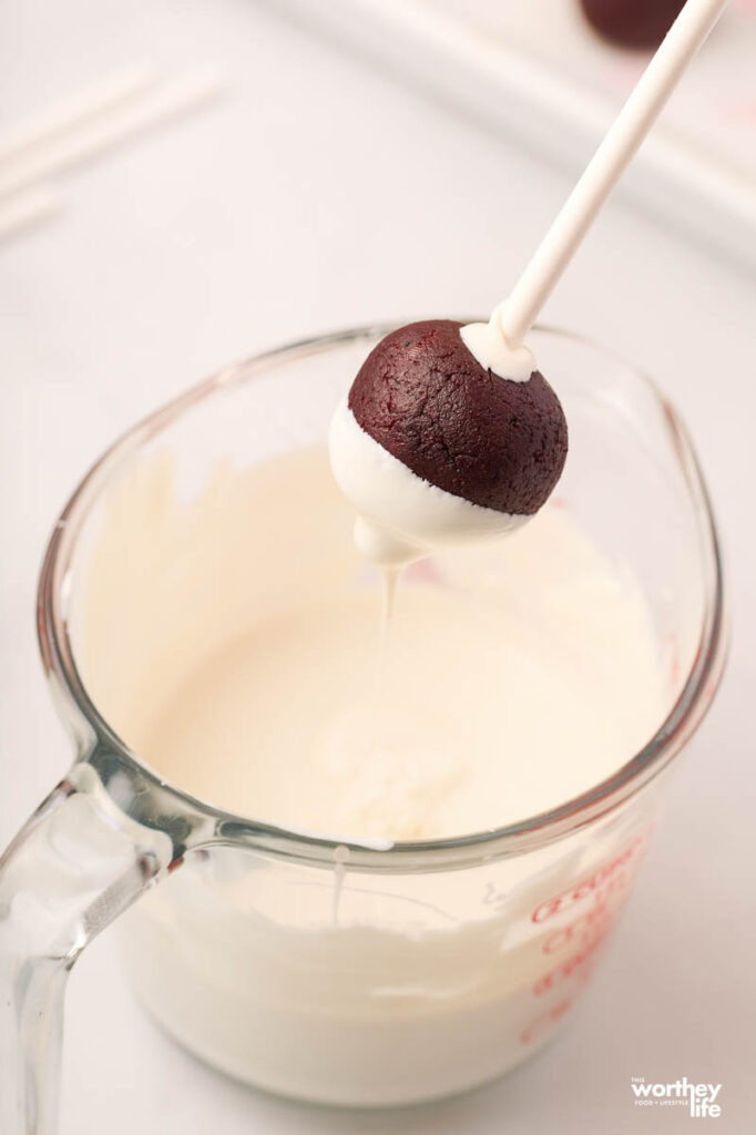 dipping cake ball into white frosting