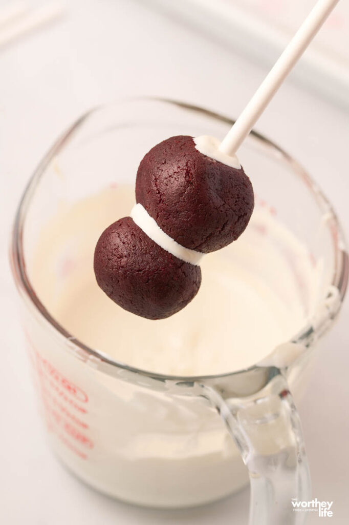 dipping cake ball into white frosting