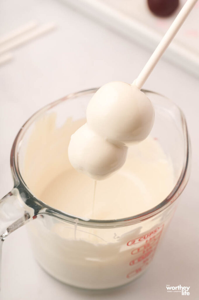 dipping cake ball into white frosting