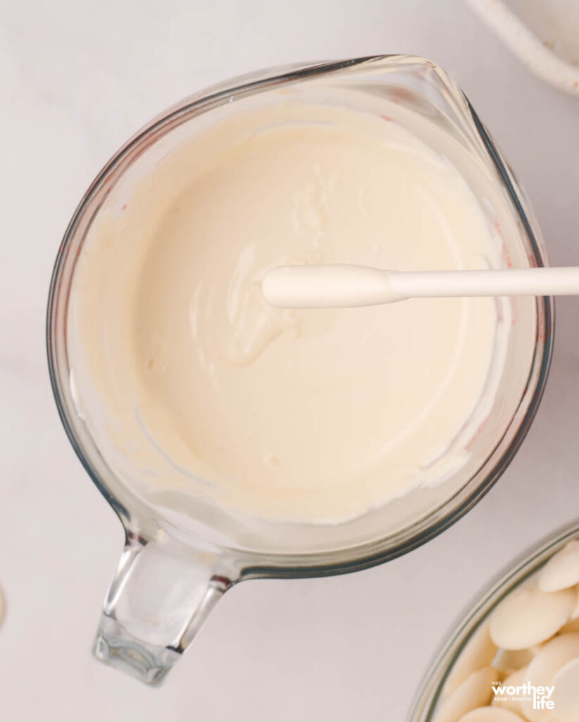 mixing white frosting in a measuring cup