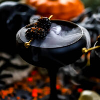 a pomegranate drink made with apple cider and lemon juice in a black glass