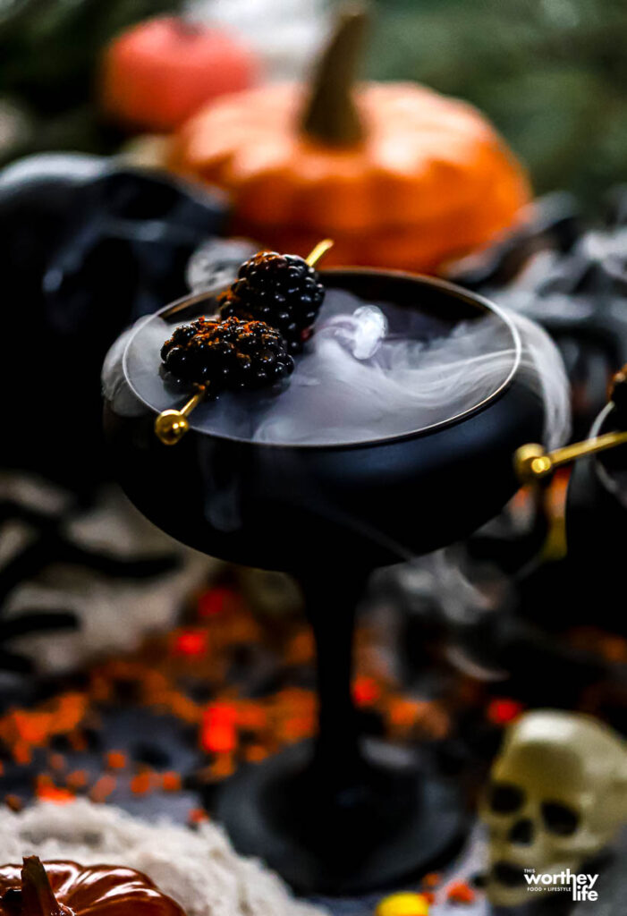 a pomegranate drink made with apple cider and lemon juice in a black glass