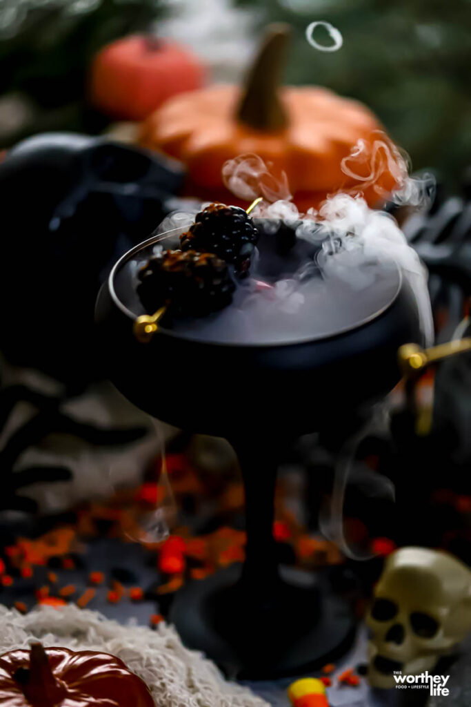 A pomegranate mocktail overflowing with the smoke form dry ice