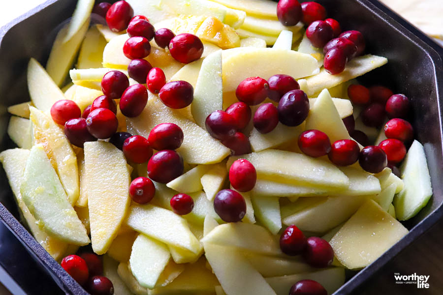 a baking dish filled with sliced apples and cranberries