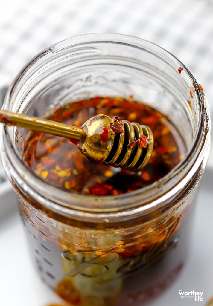 hot honey in a glass jar with a ribbed brass honey dipper.