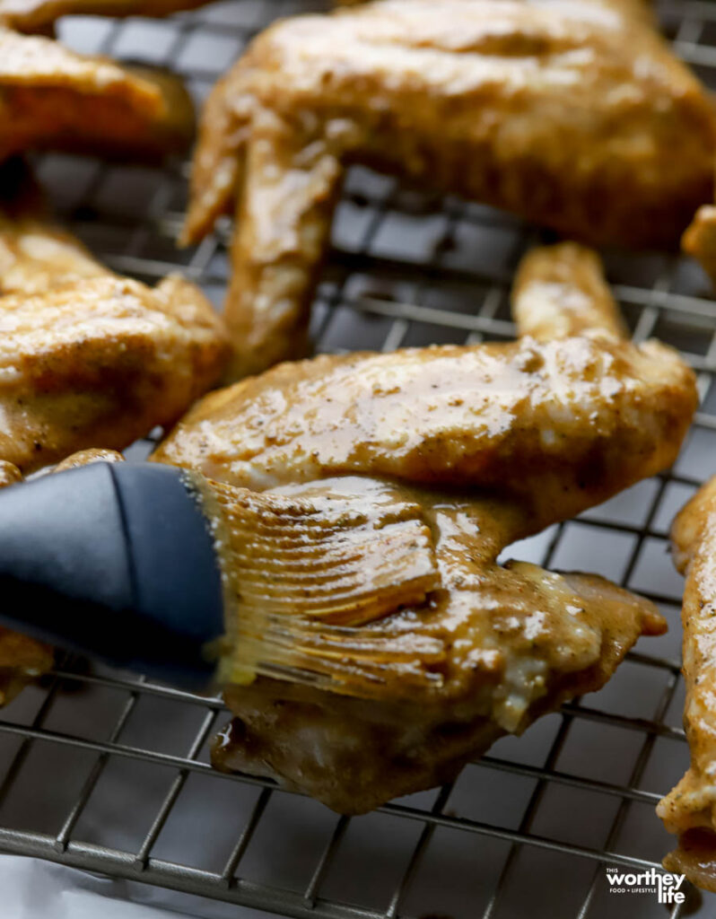 Brushing jerk seasoning marinade on chicken wing